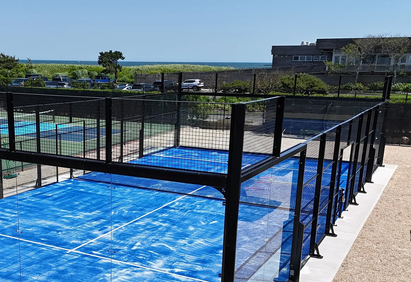 Panoramic padel court with glass walls at a beachfront club in the Hamptons, New York